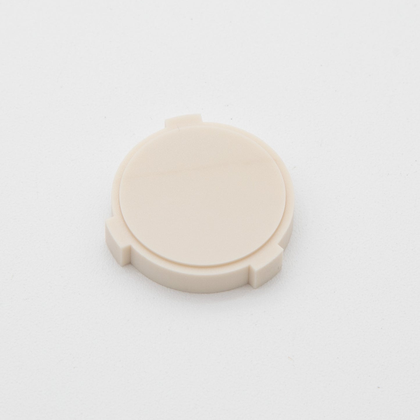 A round tan object placed on a uniform white background, highlighting its subtle design and texture.