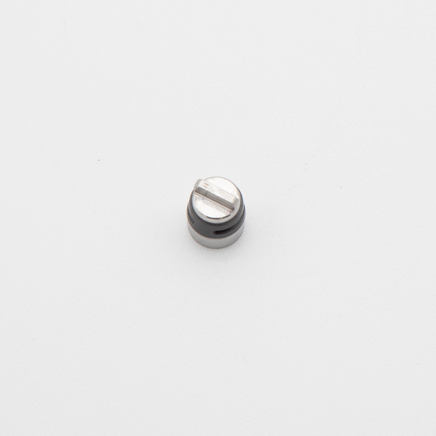 A small metal object resting on a clean white surface, showcasing its reflective surface and intricate details.
