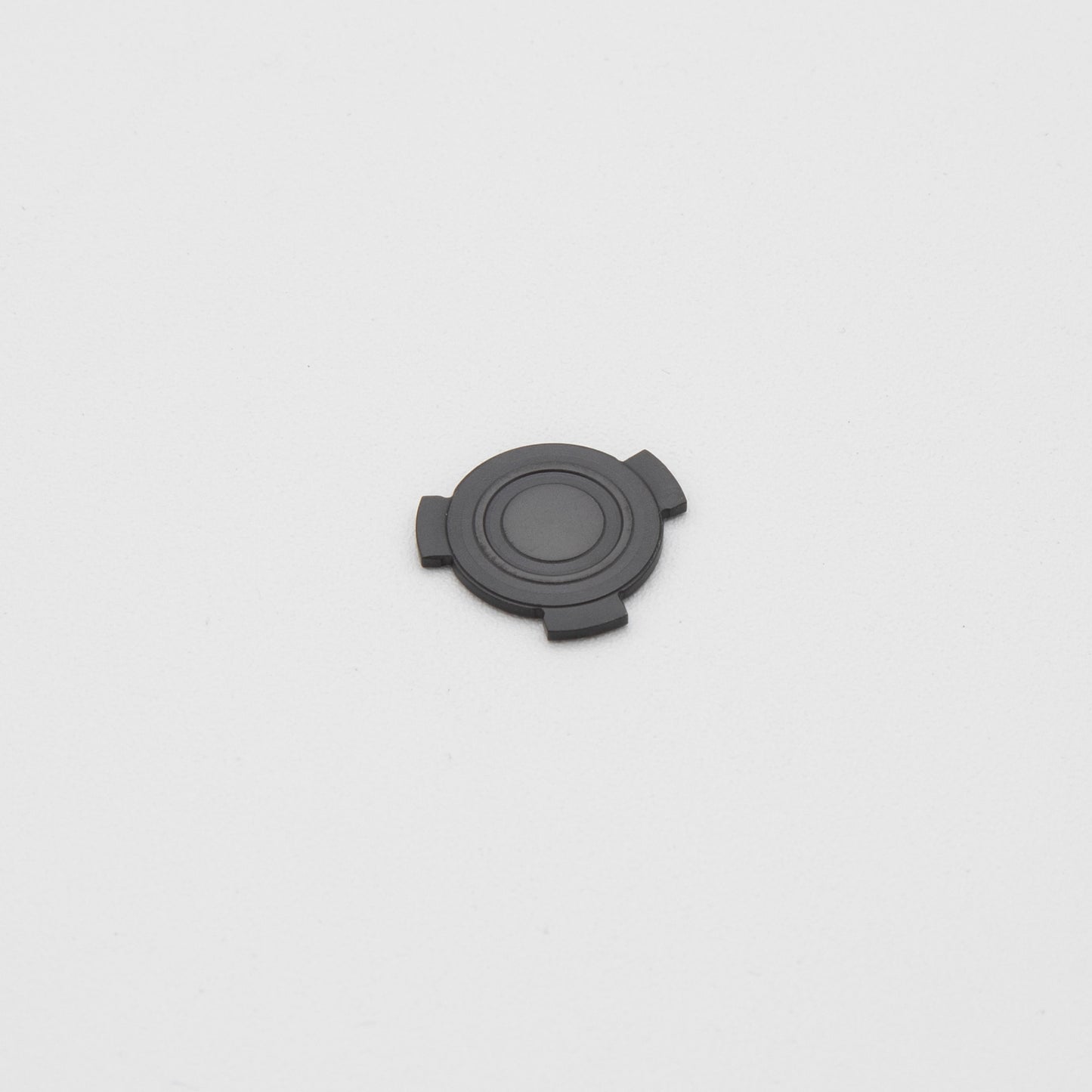 A round black plastic object resting on a clean white surface, showcasing its smooth texture and simple design.