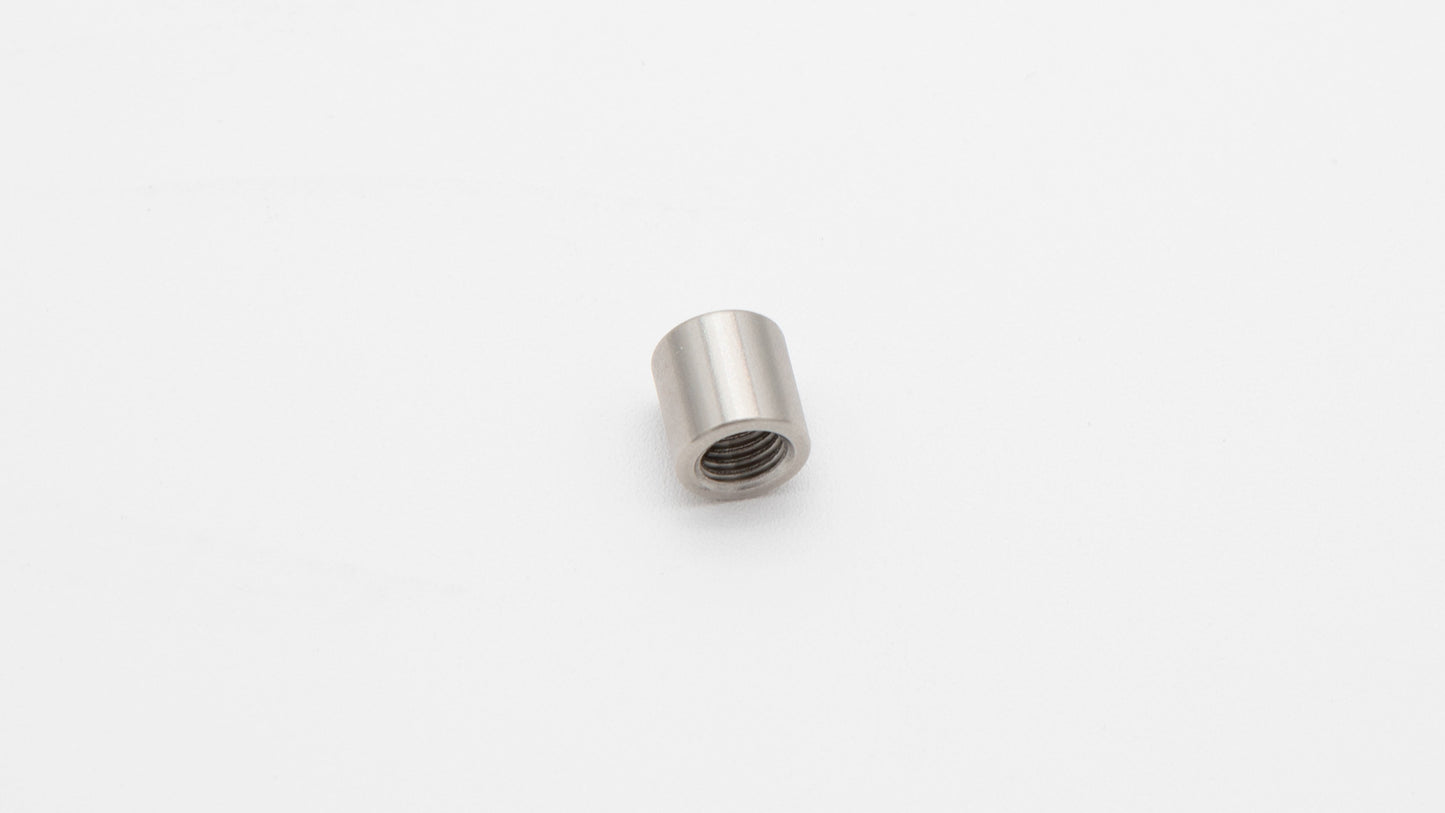 A close-up of a stainless steel nut resting on a clean white surface, showcasing its metallic texture and design.