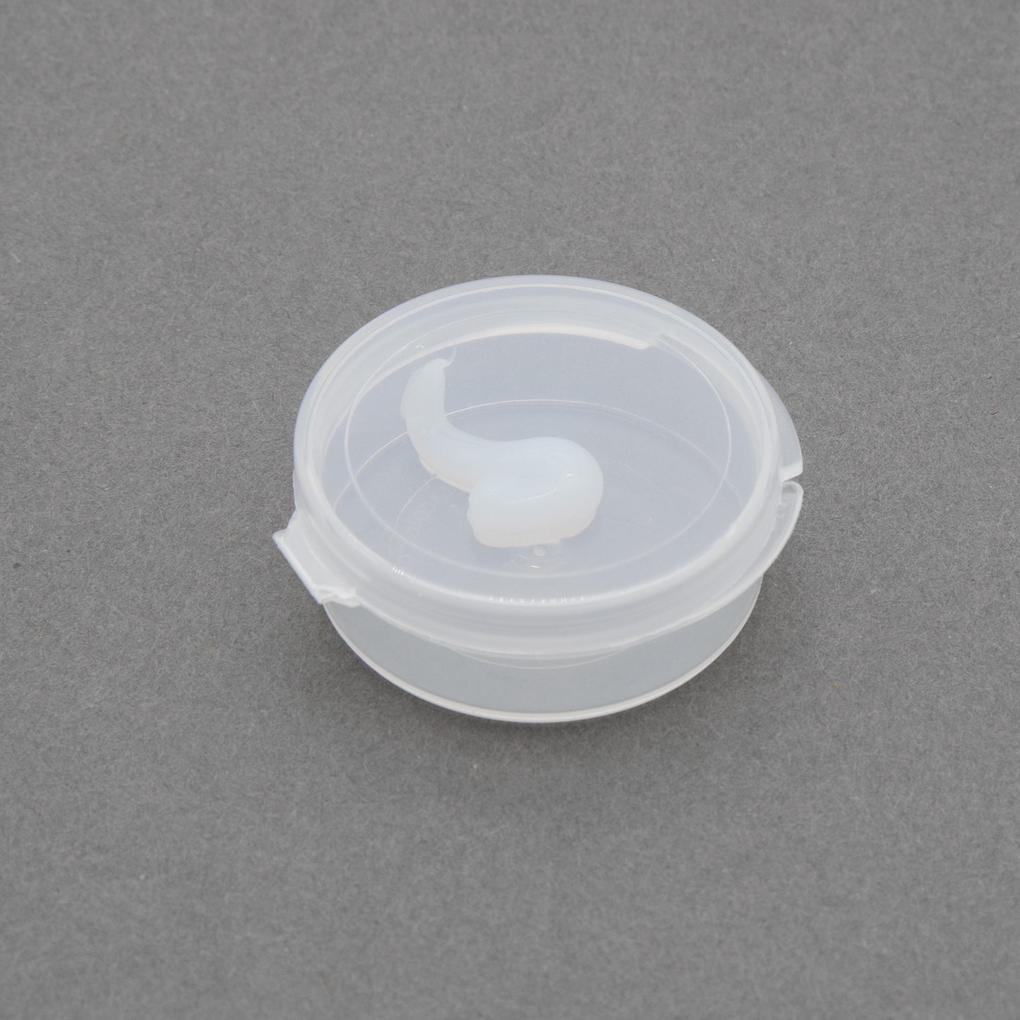 A small plastic container with a lid, containing a small amount of gel inside, placed on a neutral background.