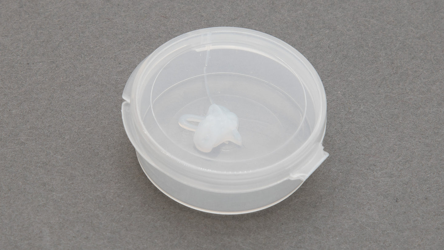 A plastic container with a lid placed on a gray surface, showcasing its simple design and functionality.