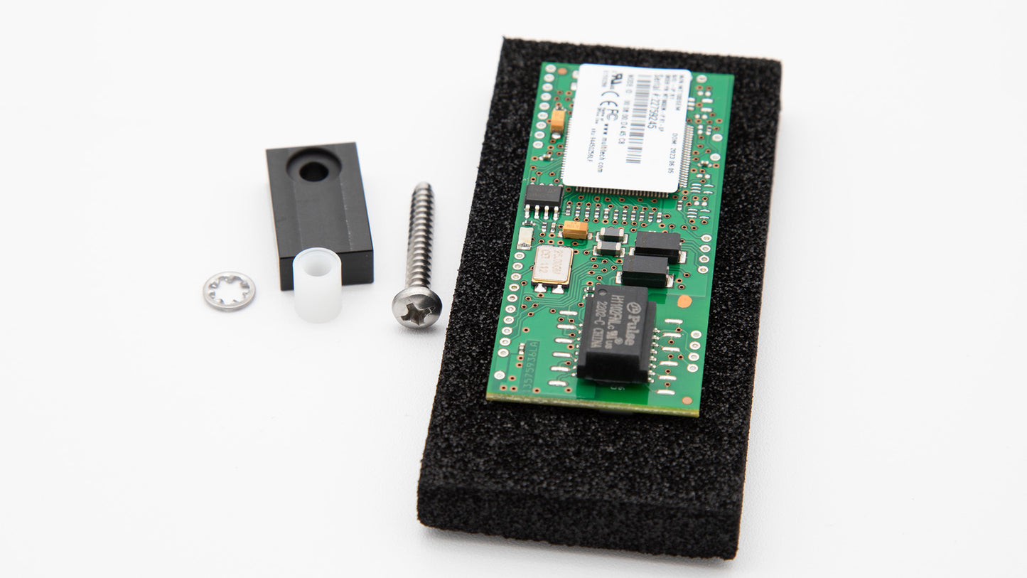 A small electronic device surrounded by a retainer and other hardware.