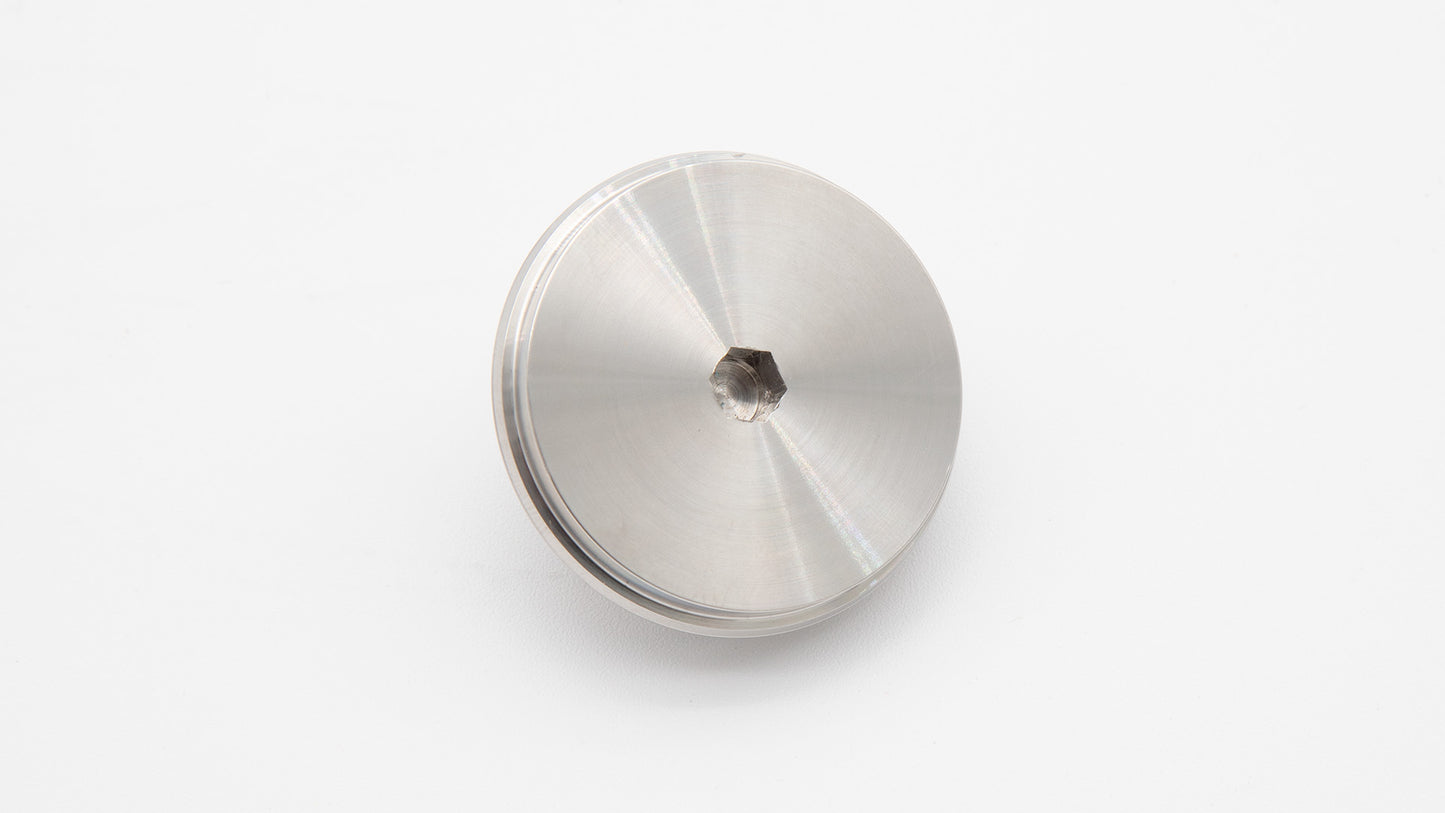 A silver metal object resting on a clean white surface, reflecting light and showcasing its sleek design.