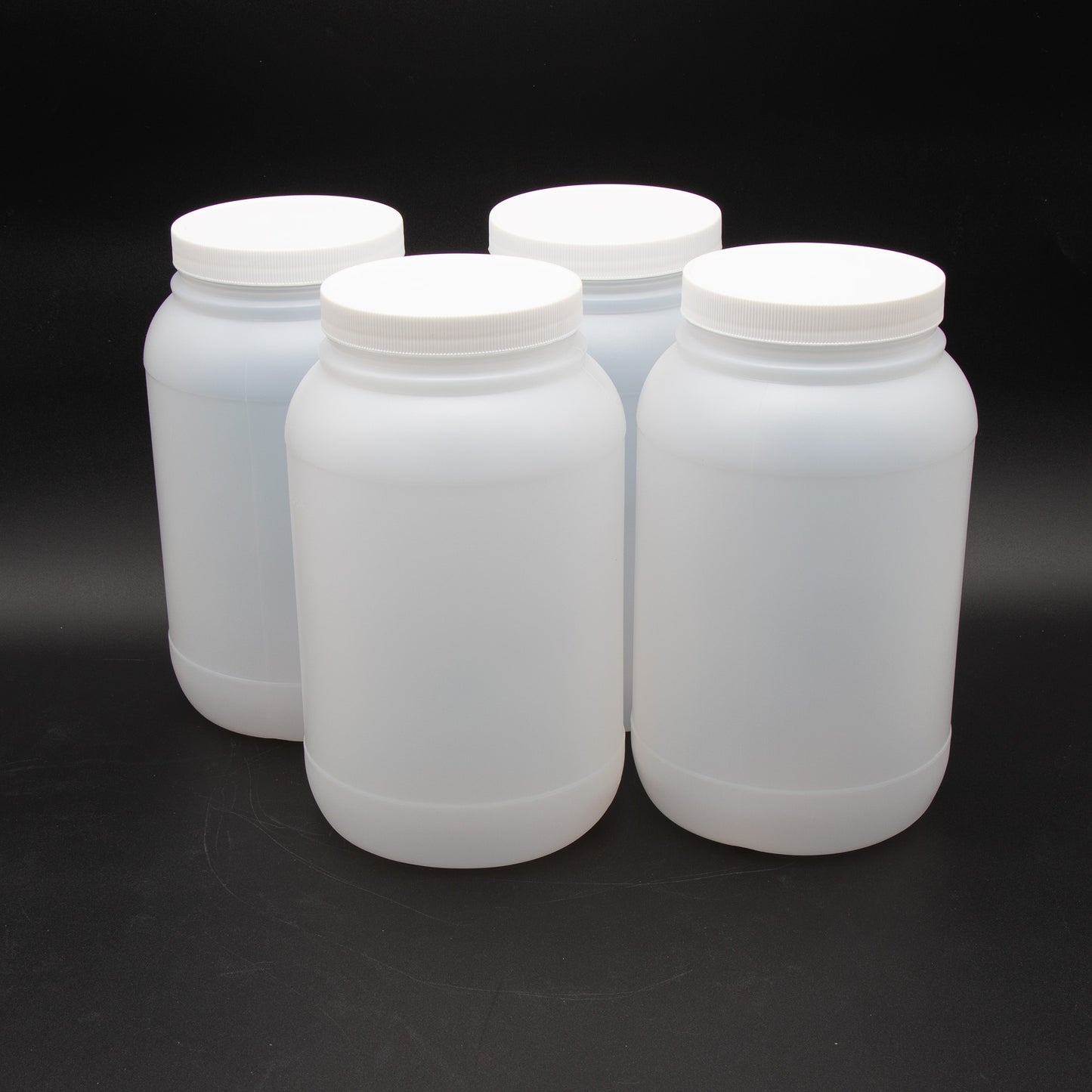 Four white plastic containers with lids arranged neatly on a black background, showcasing their clean and simple design.