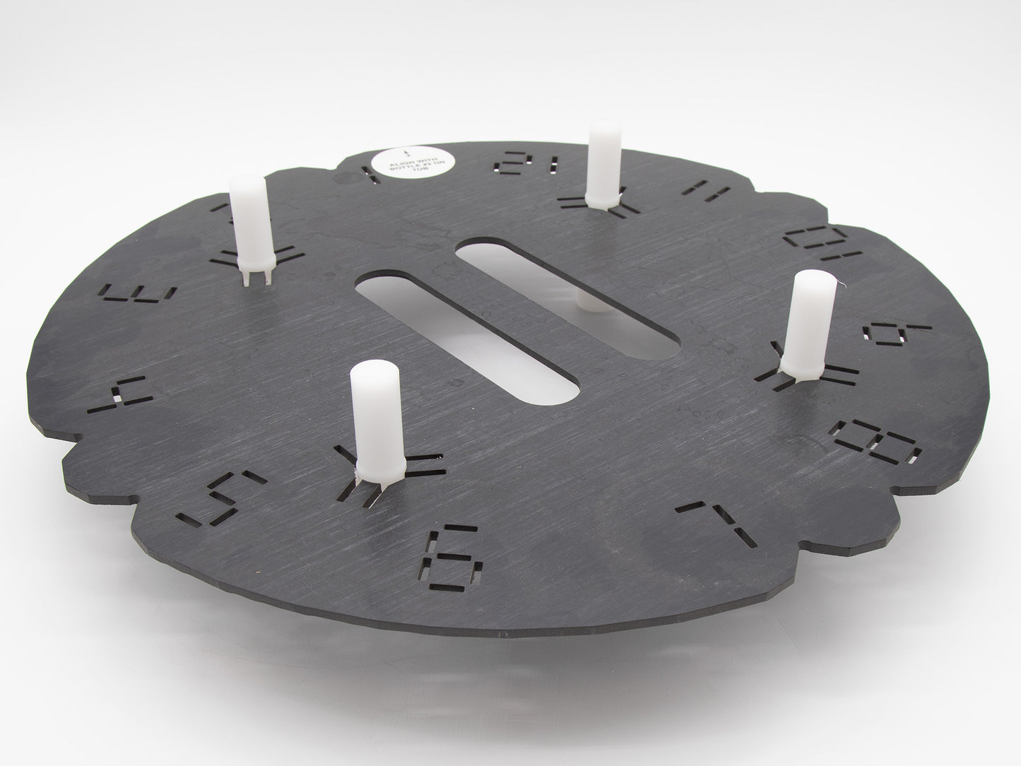 Circular shaped black plastic object with indented numerals.