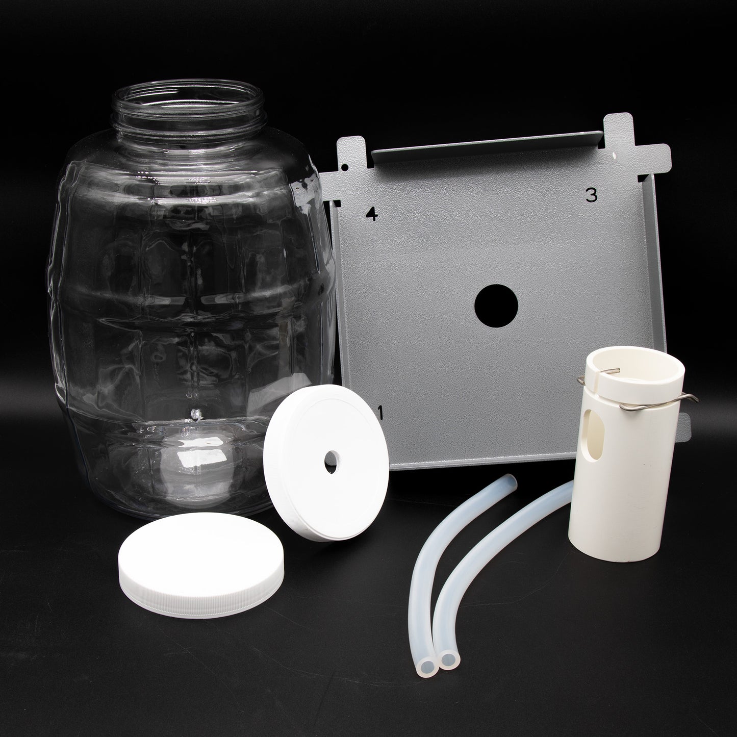 A white plastic container with lid, plastic hoses, locating deck and hose routing device.