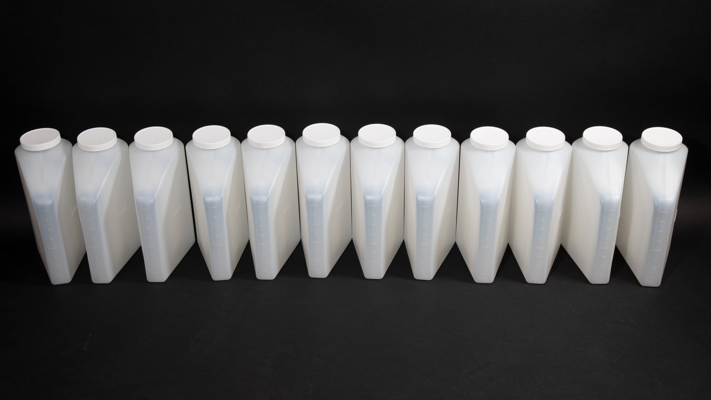 A row of white plastic bottles with lids arranged neatly on a surface, showcasing their uniform design and color.