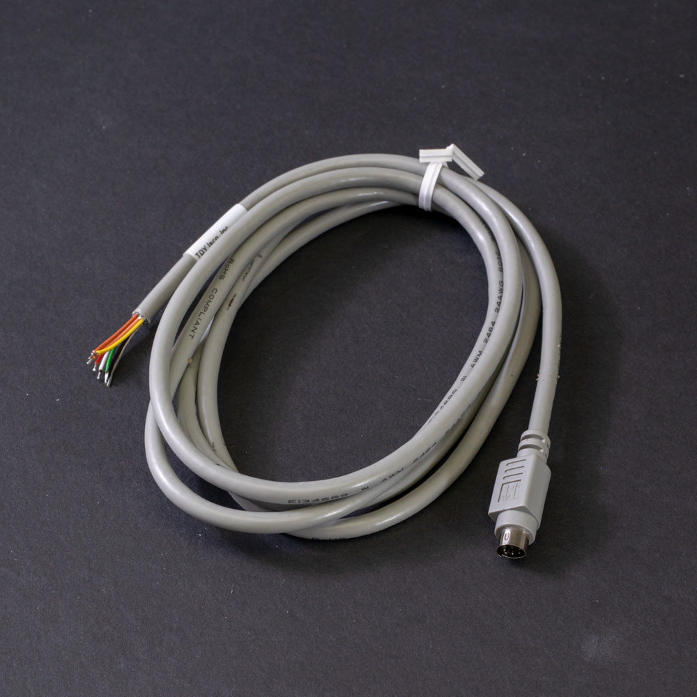 A grey cable with a plug rests on a black surface, emphasizing the sleek and modern aesthetic of the setup.