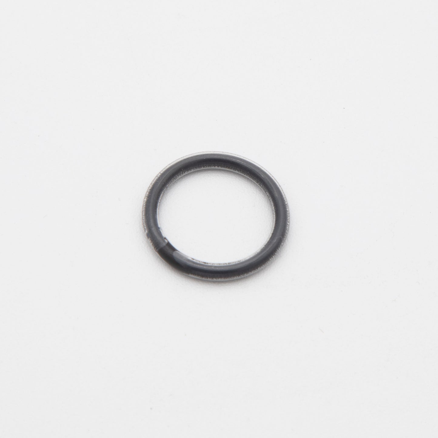 A black rubber ring placed on a clean white surface, showcasing its smooth texture and circular shape.