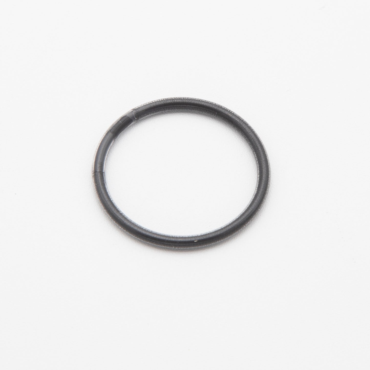 A sleek black ring resting on a smooth white surface, showcasing a striking contrast between the two colors.
