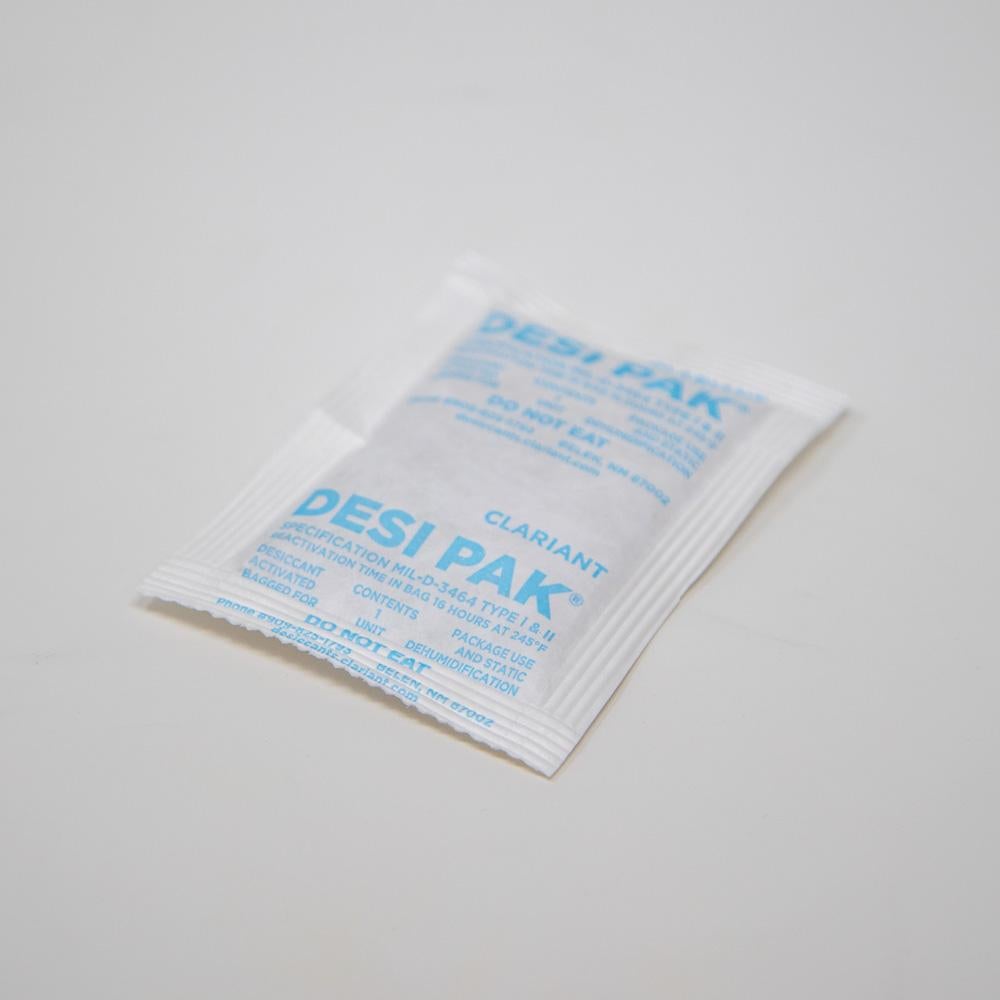 A small white bag of desiccant resting on a sleek white surface.