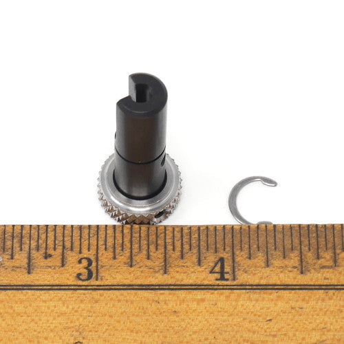 A detailed view of a black and silver threaded metal object highlighting its unique threading and metallic finish posed next to a ruler.