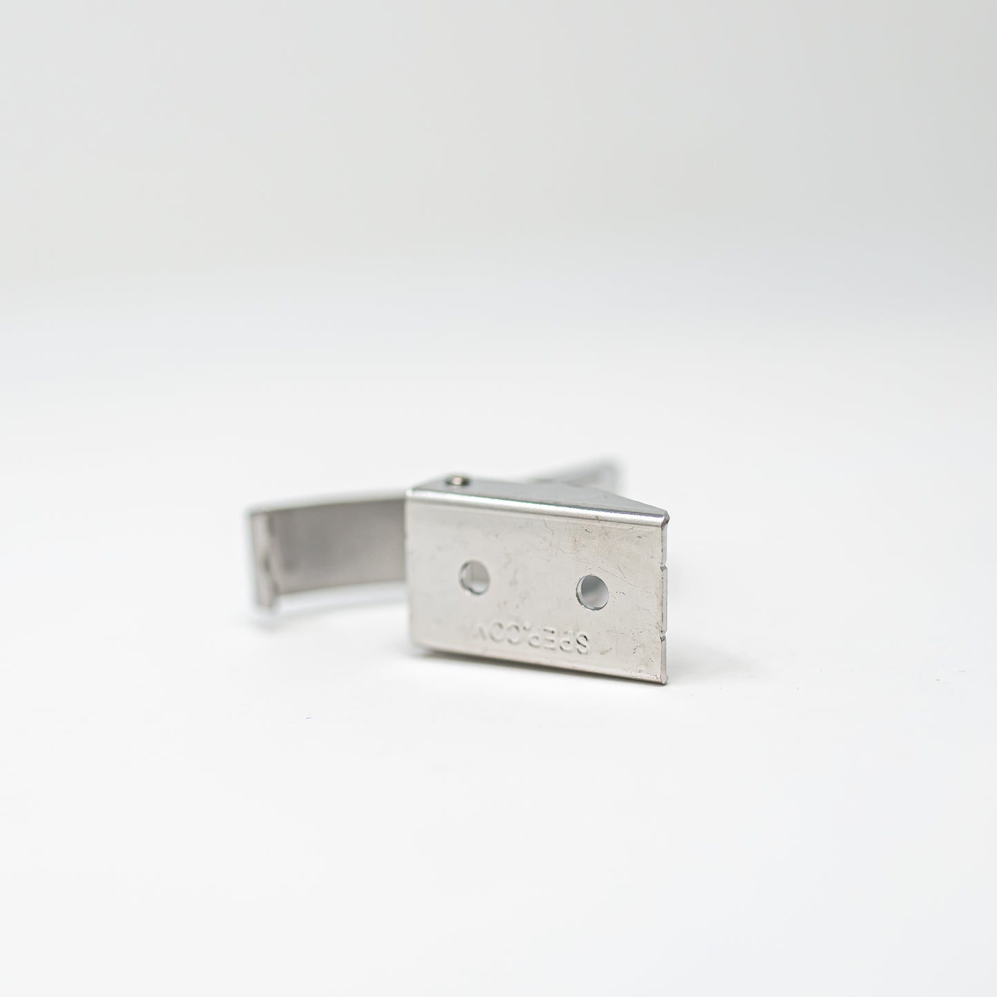 A silver metal latch placed on a white surface, emphasizing its polished appearance and simple elegance.
