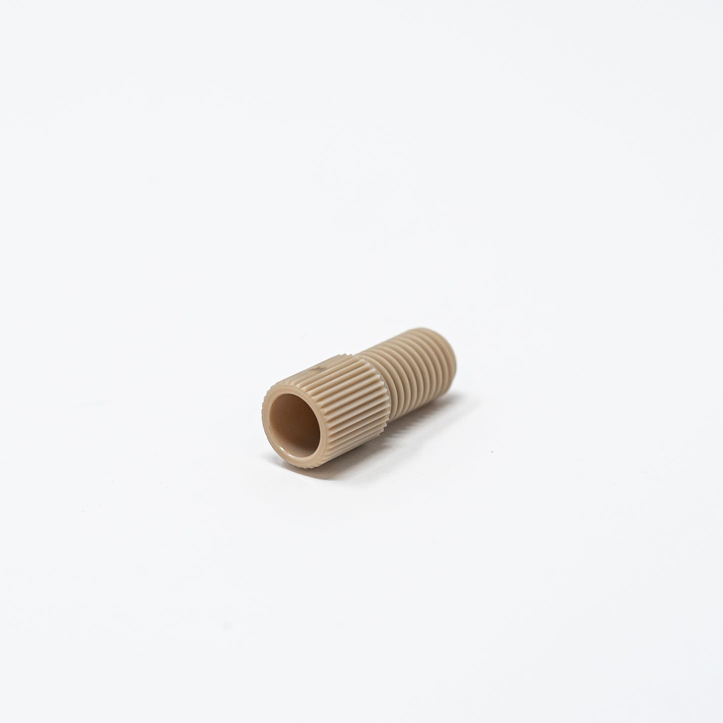A tan threaded nut resting on a clean white surface, showcasing its simple design and color contrast.