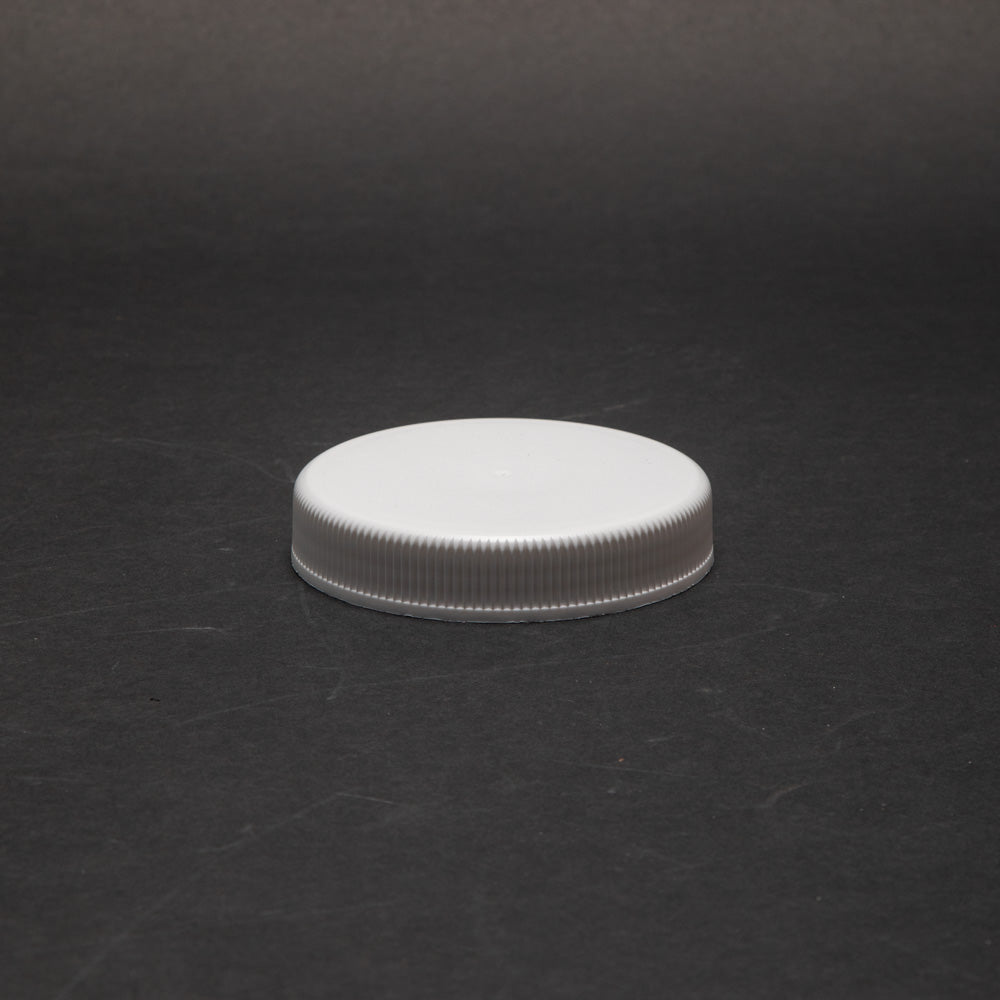 A white plastic cap positioned on a dark black surface, emphasizing the visual difference between the two elements.