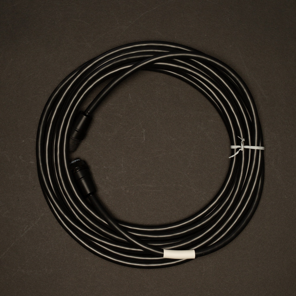 A black cable with connectors on both ends are positioned on a black surface, showcasing their distinct colors against the dark background.