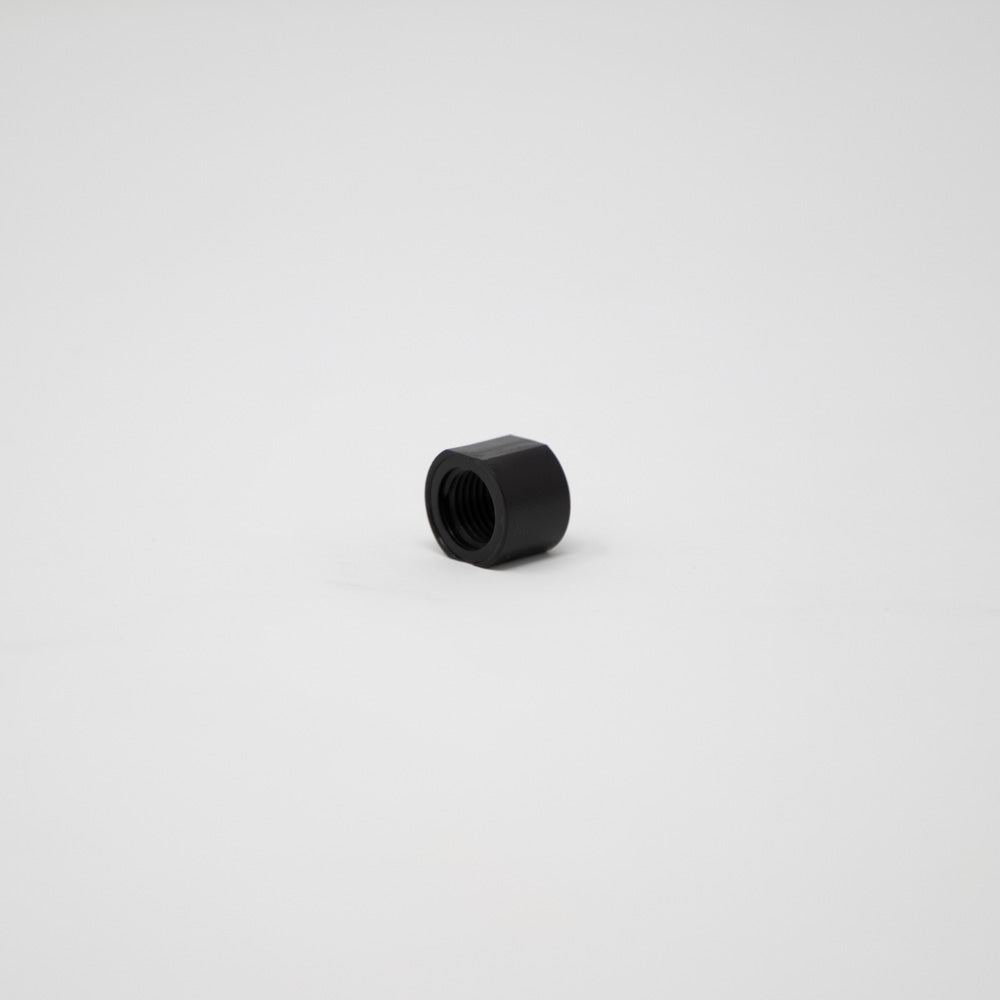 A black plastic nut resting on a clean white surface, showcasing its smooth texture and simple design.