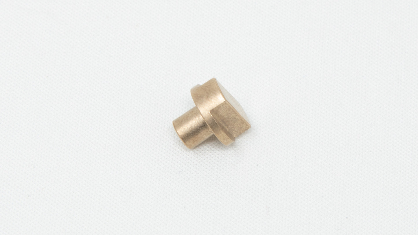 A brass-colored bearing resting on a smooth white surface, showcasing its metallic sheen and simple design.