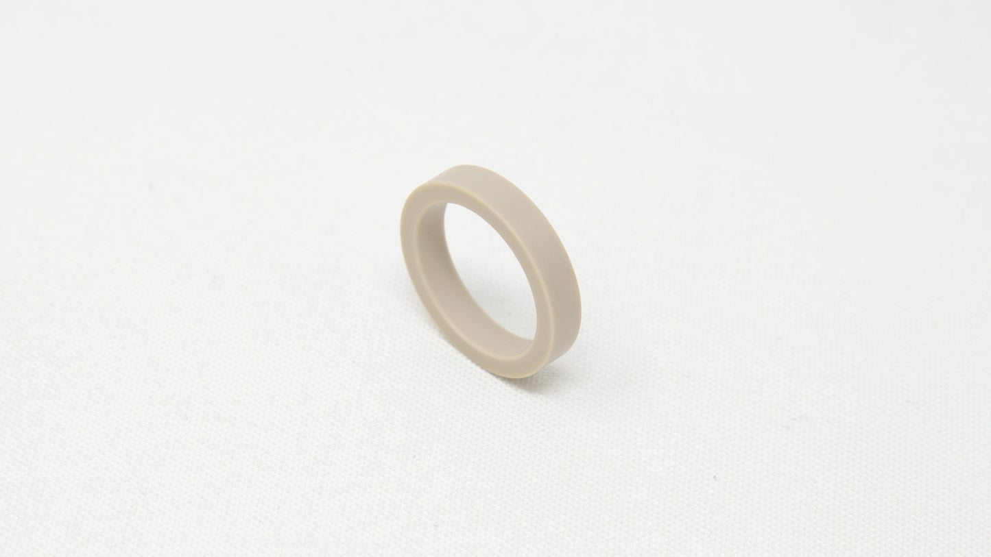 A tan colored ring, elegantly placed on a pristine white surface.
