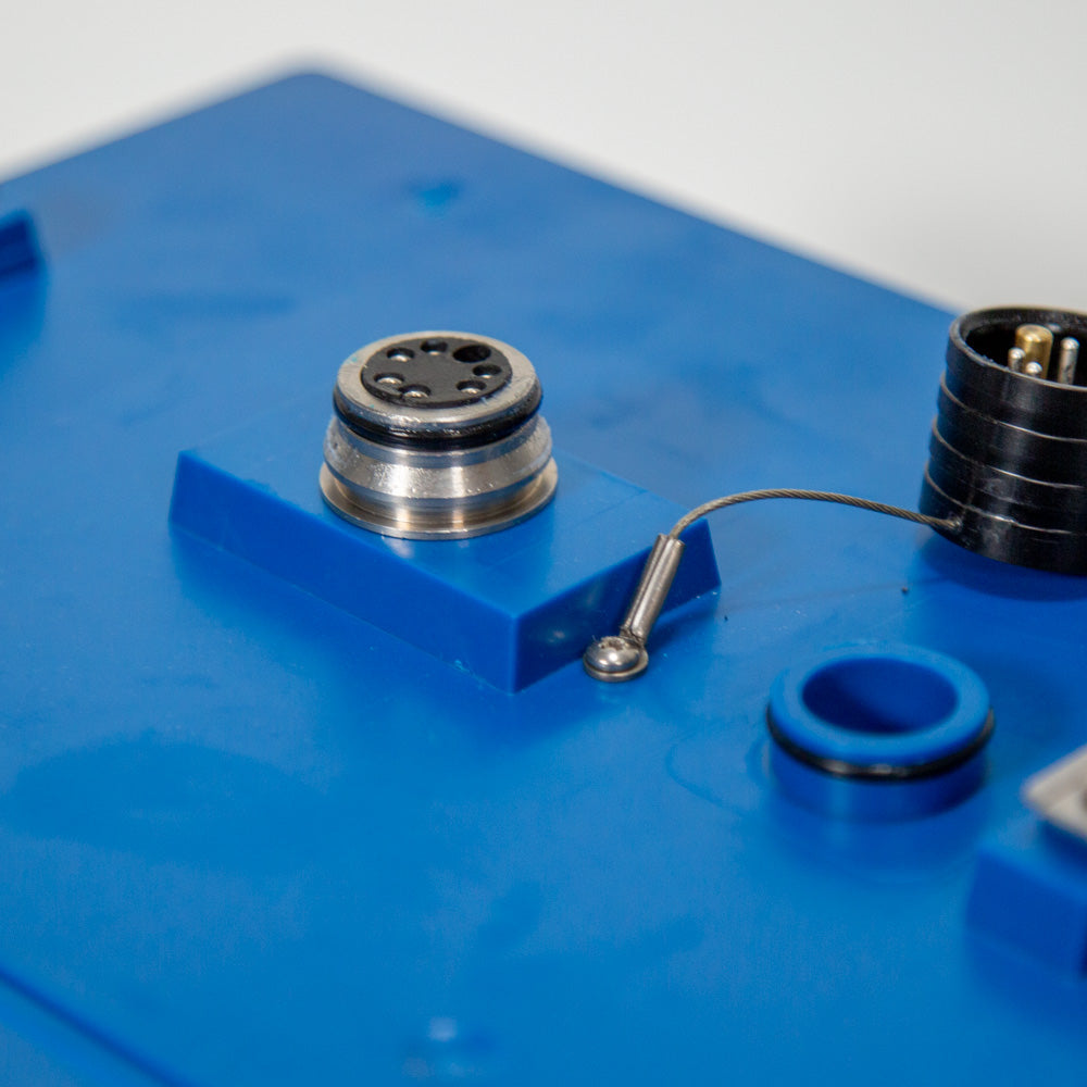 A close-up of a blue box with a connector and cap, showcasing essential tools for connecting cables.