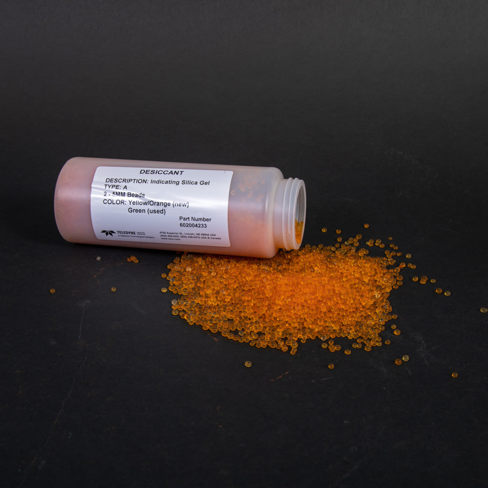 A bottle of orange beads placed on a wooden table, showcasing its vibrant color against the natural surface.