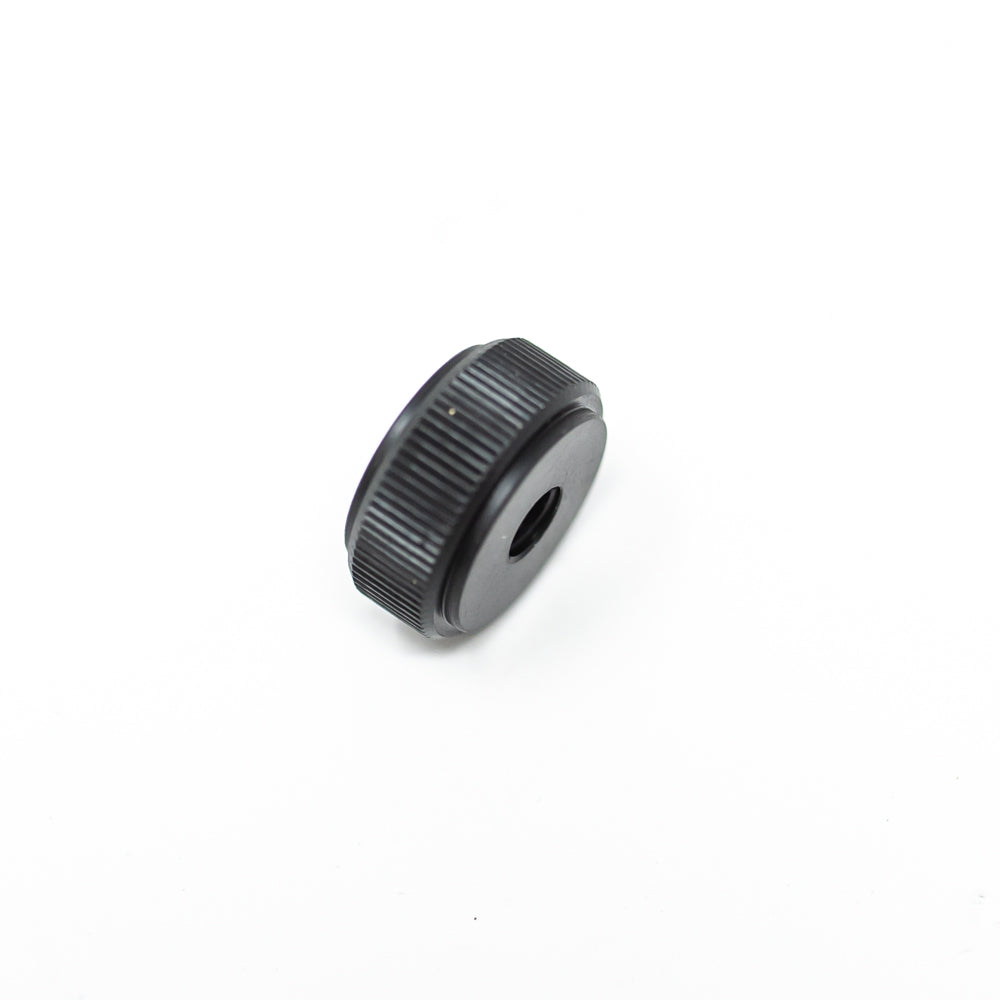 A black plastic nut placed on a white surface, emphasizing the contrast between the dark knob and the light background.