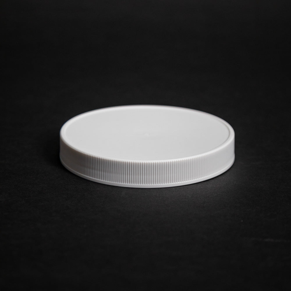 A white plastic lid resting on a smooth black surface, showcasing a contrast between the two colors.