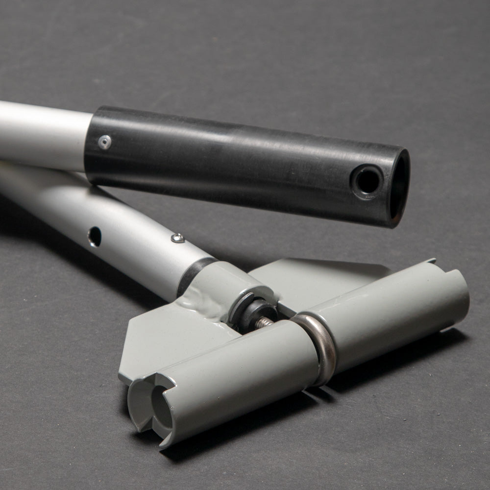 Two metal poles with a special connector positioned on a gray surface, creating a simple yet functional arrangement.