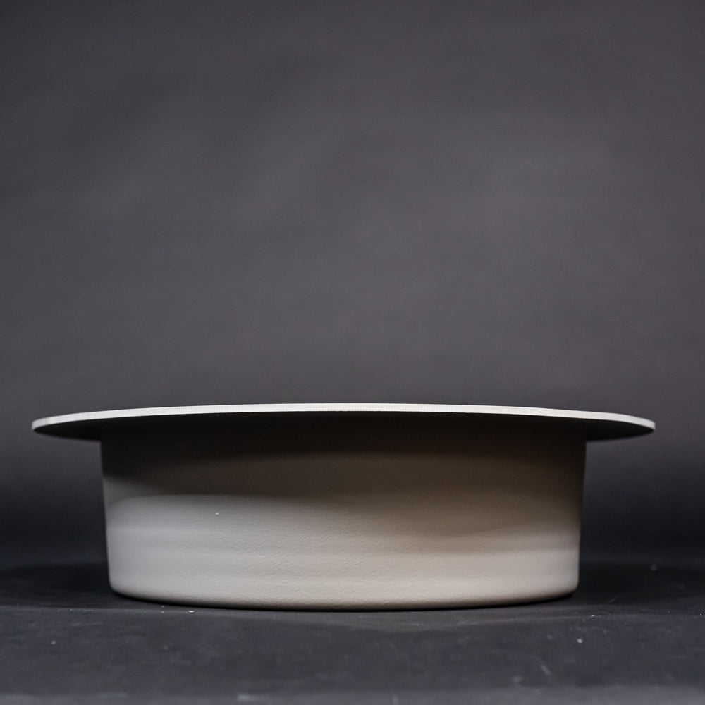 A grey bowl shaped object with a lip, showcasing a simple and elegant design.