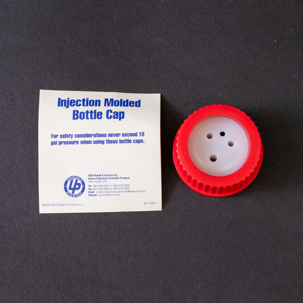 A red plastic cap featuring a white plug, typically used for securing liquid containers.