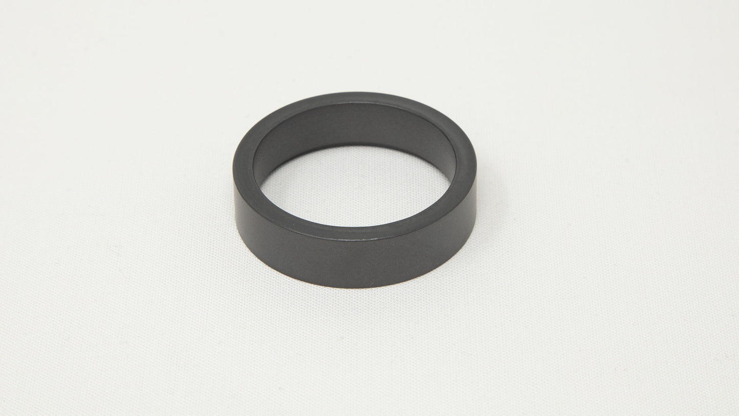 A sleek black ring resting on a smooth white surface, showcasing a striking contrast between the two colors.