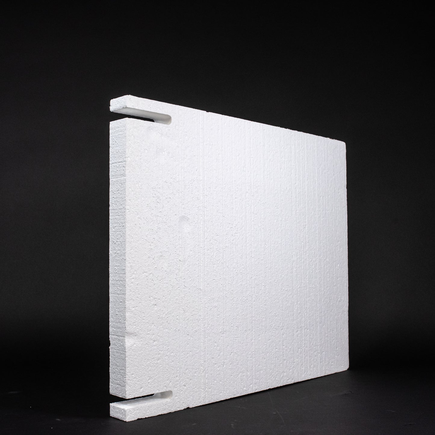 A white foam block positioned on a sleek black surface, creating a striking contrast between the two colors.