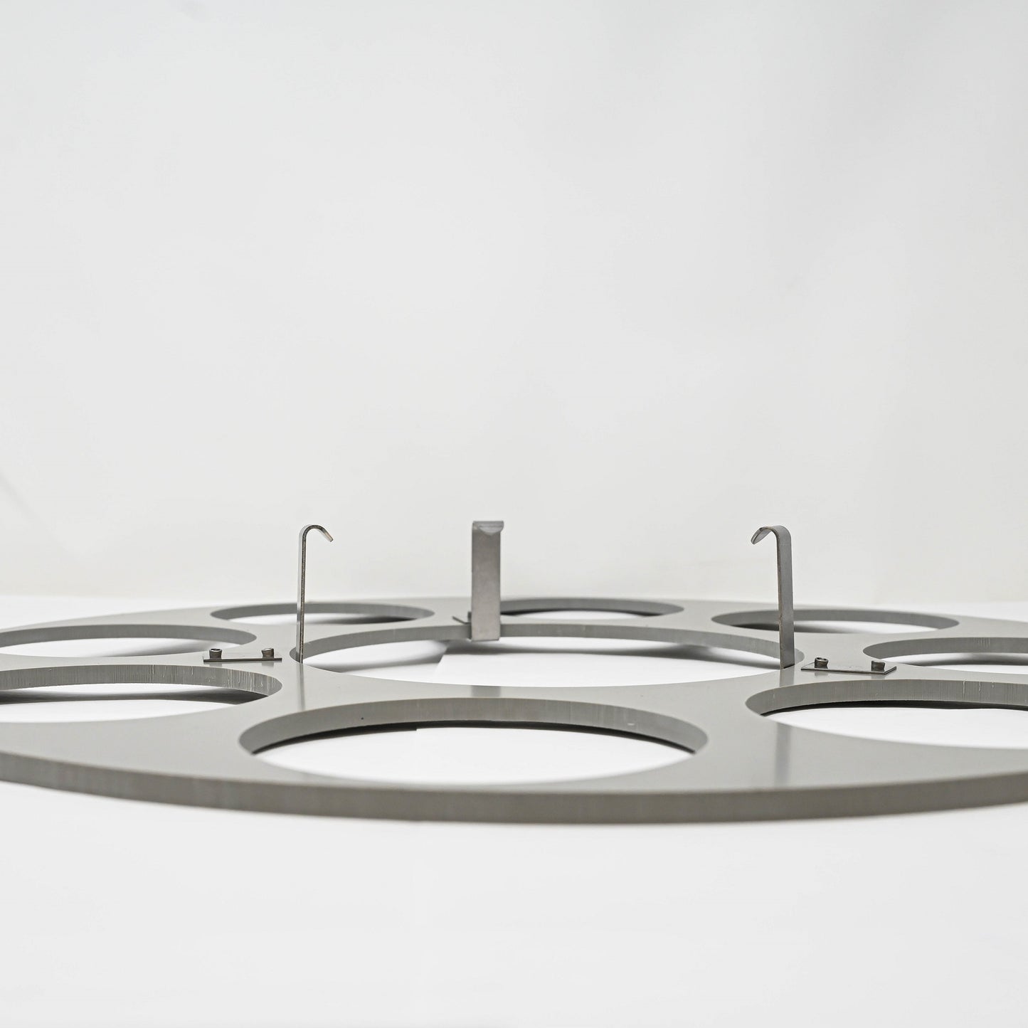 A circular metal plate featuring multiple holes designed for securely holding bottles.