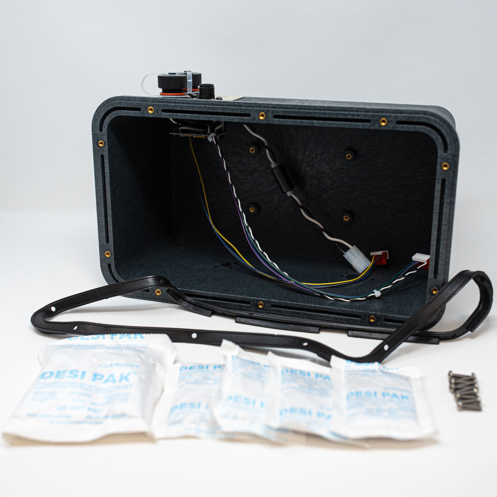 A black case with visible wires, screws and desiccant, representing a compact electronic component arrangement.