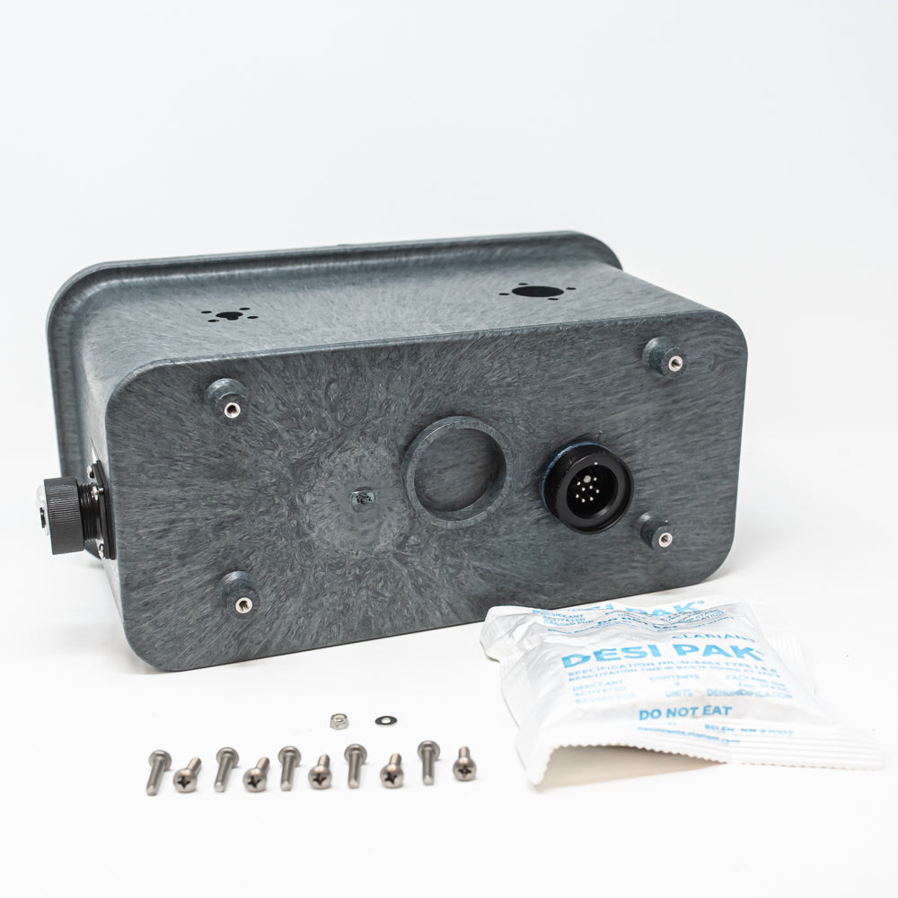 A black box with multiple wires attached, next to a desiccant bag, representing a configuration of electronic devices.