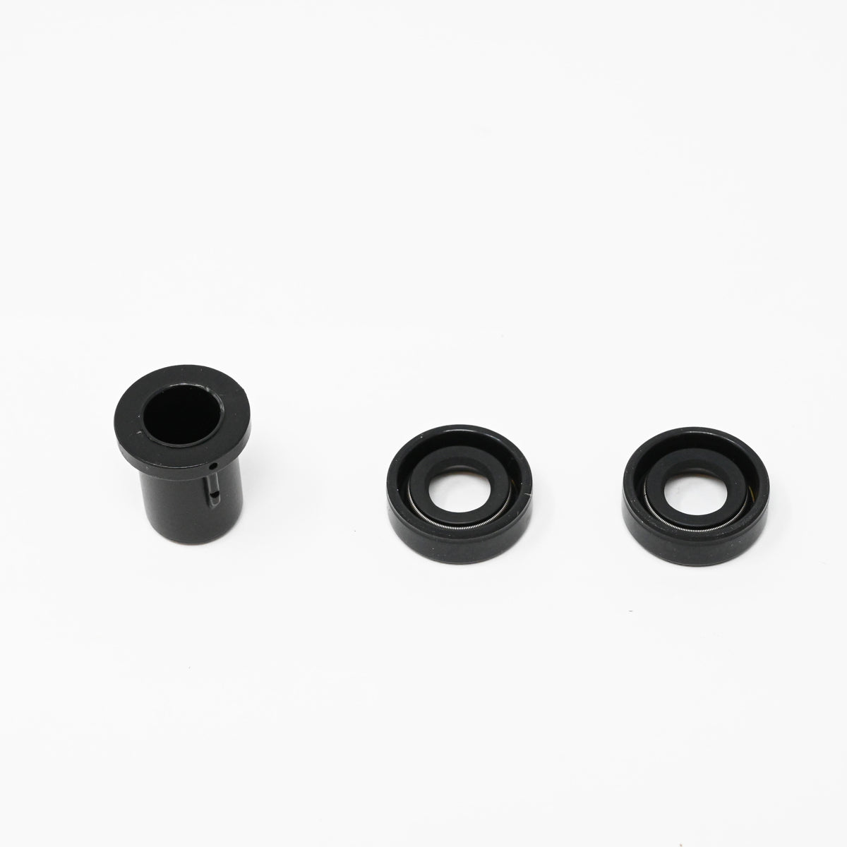 A set of black rubber bushings positioned on a white surface, showcasing their texture and shape.