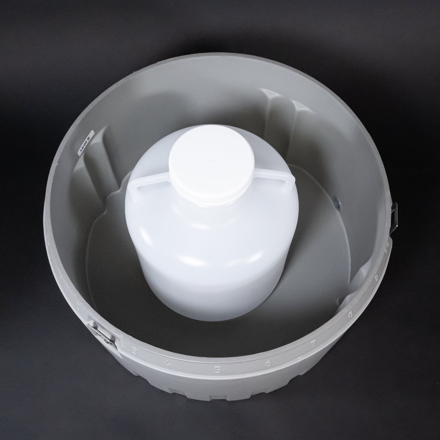 A gray bucket containing a white plastic jug, illustrating a practical storage solution.