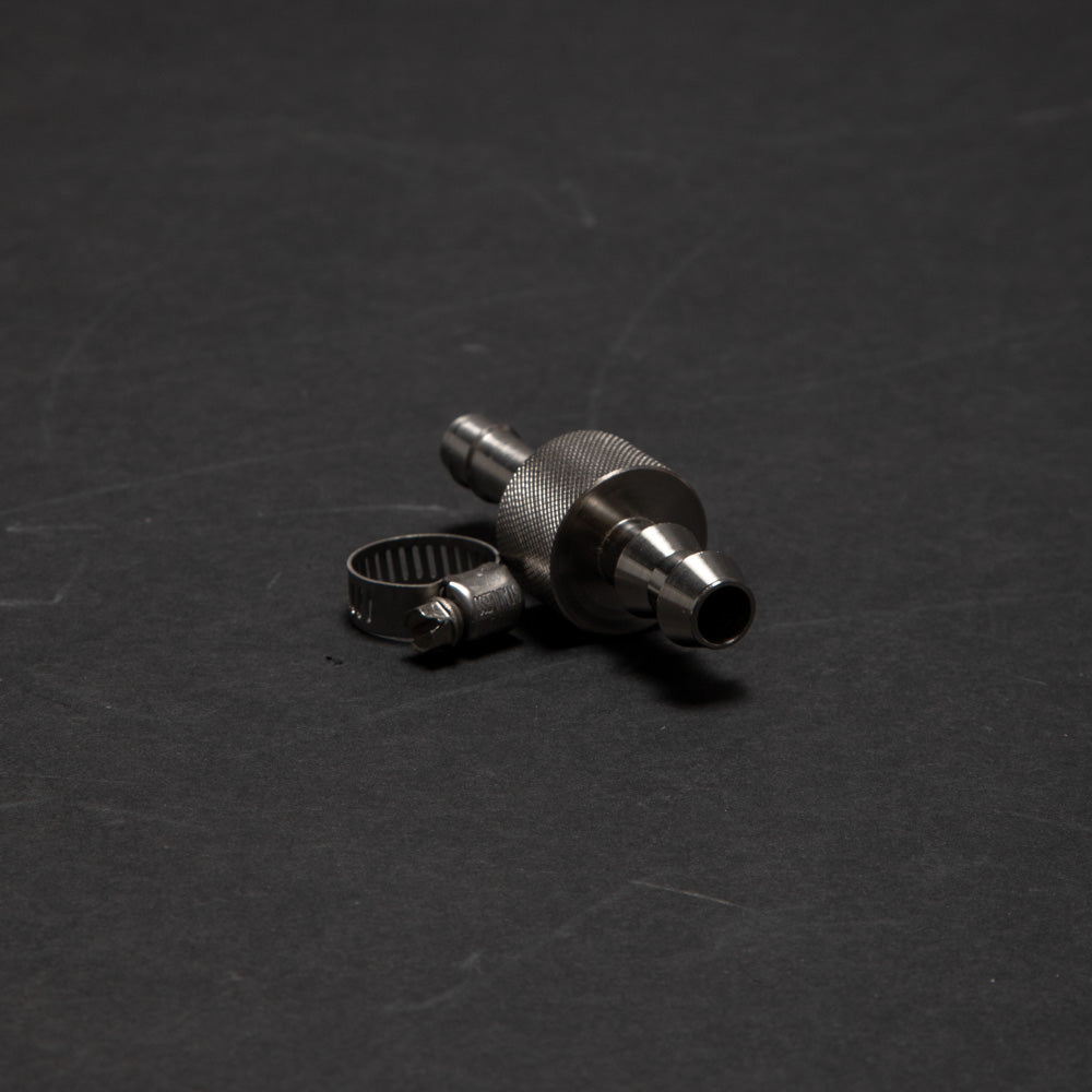 A small metal device with a clamp positioned on a smooth black surface, showcasing its metallic finish and compact design.