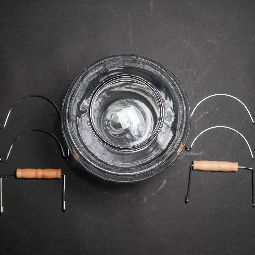 A jar with a lid and a wooden handle, showcasing a simple and functional design for storage or transport purposes.