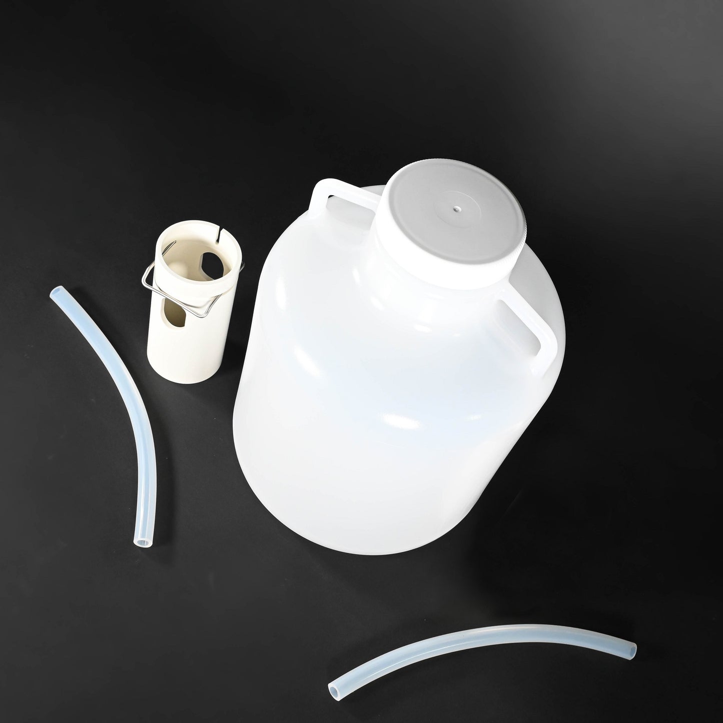 A white plastic jug connected to a hose and a plastic tube, designed for fluid transfer or dispensing purposes.