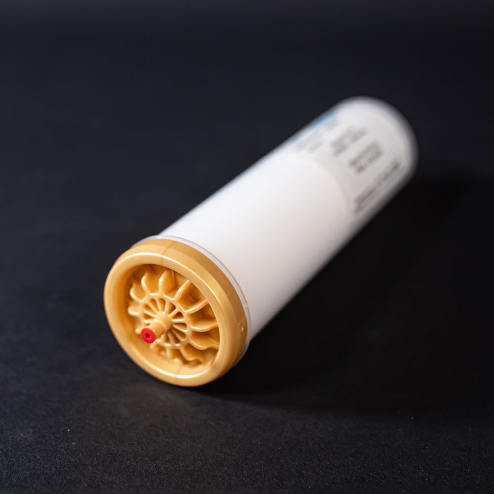 A small white tube with gold and red caps displayed on a black background, creating a striking visual contrast between the two elements.