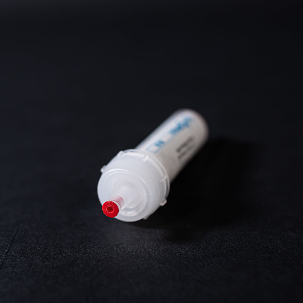 A small white tube with red caps displayed on a black background, creating a striking visual contrast between the two elements.