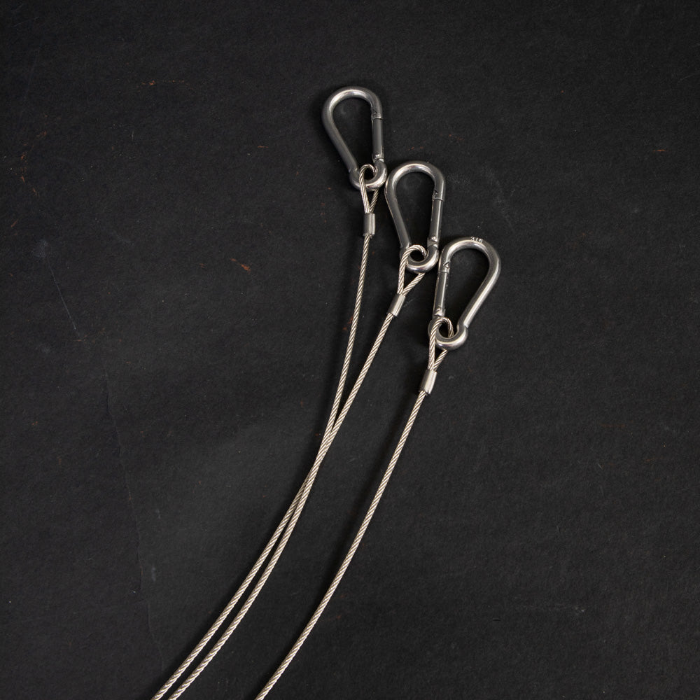 Three shiny silver hooks displayed against a dark black surface.
