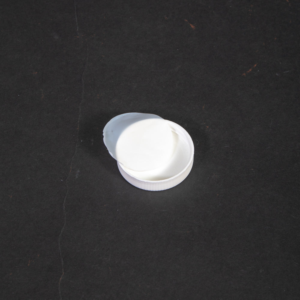 A white plastic cap arranged on a smooth black surface.