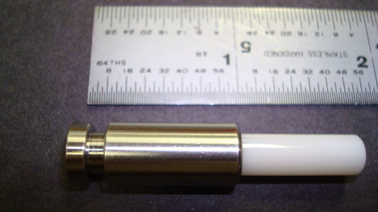 A metal cylinder positioned beside a ruler, illustrating a measurement context in a clear and concise manner.