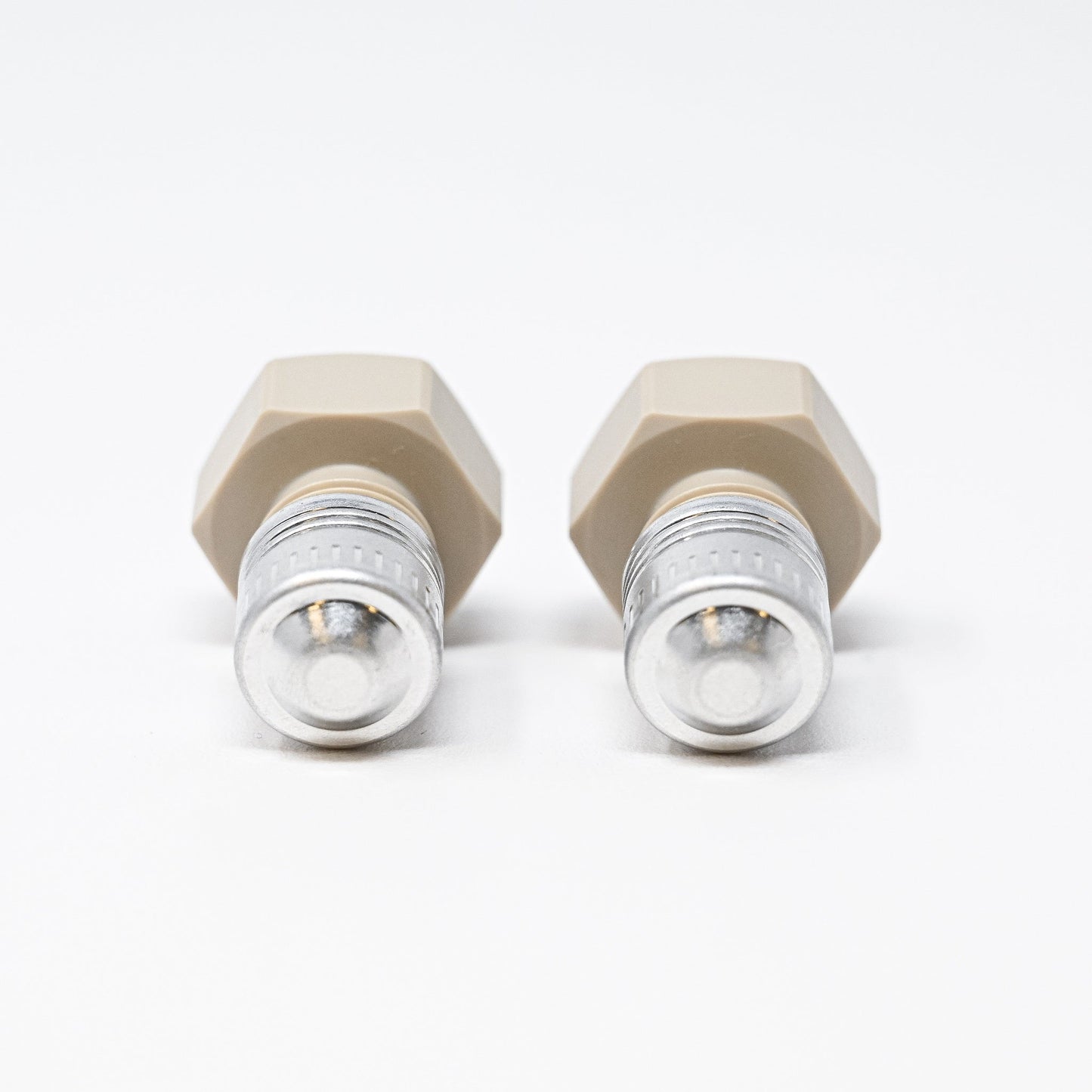 Two white plastic hexagon-shaped plugs resting on a clean white surface, showcasing their geometric design.