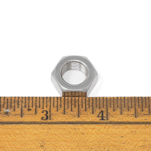 A small nut positioned on a ruler, illustrating size comparison between the nut and the measuring tool.