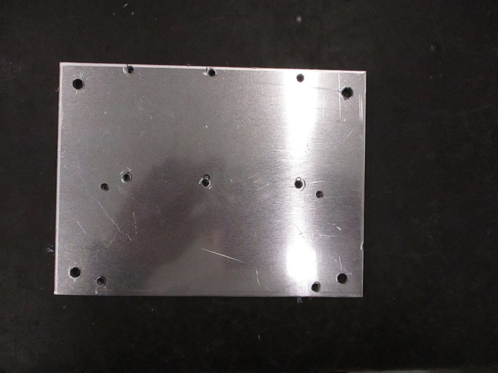 A metal plate adorned with various holes and screws, illustrating its functional design for secure attachment or support.
