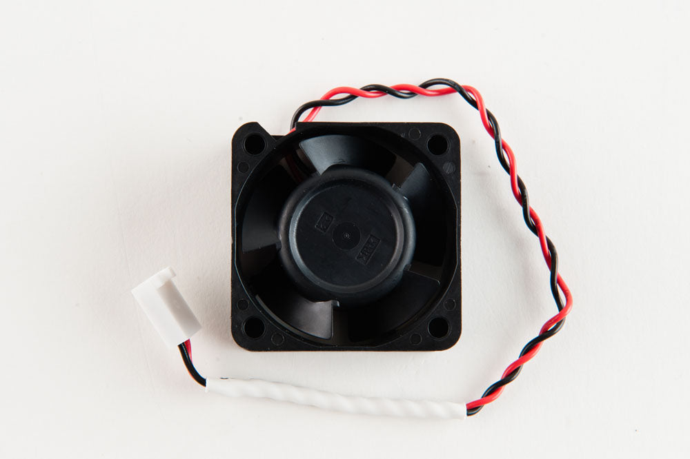A small black electric fan with wires connected, resting on a surface.